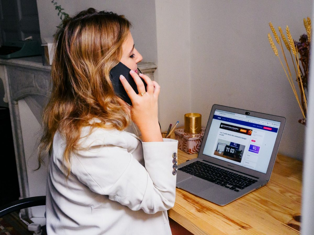 Woman working at a desk with her laptop and phone
