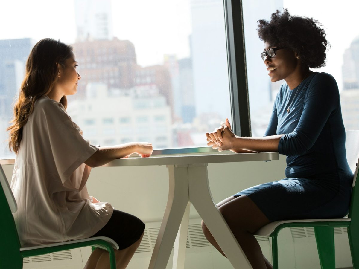 Two colleagues chatting at a table in an office